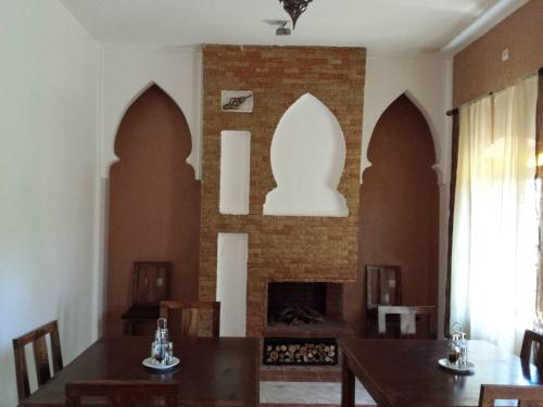 a dining room with a table and a fireplace at Riad Tazawa in Ibrahene