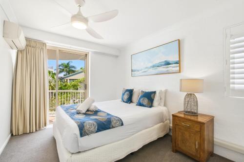 a white bedroom with a bed and a window at Osprey Apartments in Mooloolaba