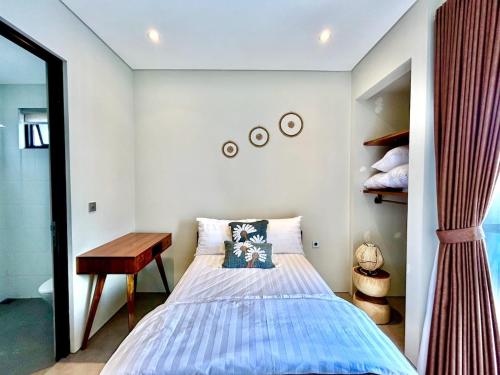 a bedroom with a bed and a wooden table at SanSan Home in Jimbaran
