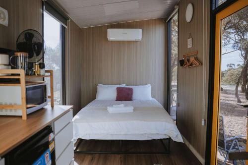a small bedroom with a bed and a window at Tallarook Hilltop Tiny House 3 by Tiny Away in Tallarook