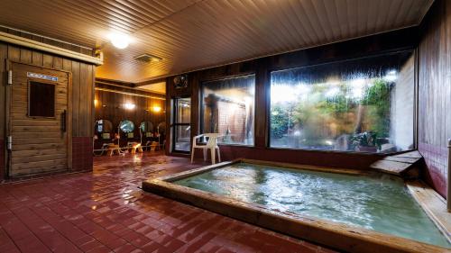 a hot tub in a room with a large window at 緑風苑 きよはる Ryokufuen Kiyoharu in Takayama