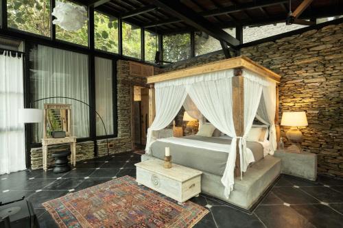 ein Schlafzimmer mit Himmelbett und Steinwand in der Unterkunft The Sen - Lansdowne in Dogadda