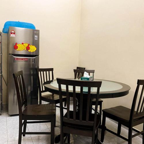 a dining room with a table and chairs and a refrigerator at Azihar Homestay Marang in Marang