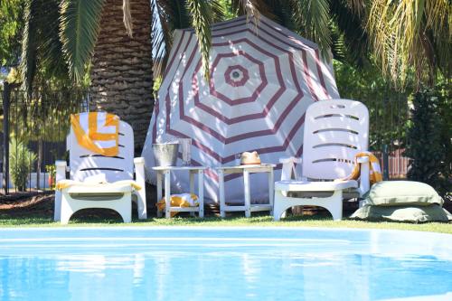 two lawn chairs and an umbrella next to a swimming pool at Billabong Motel in Gunnedah