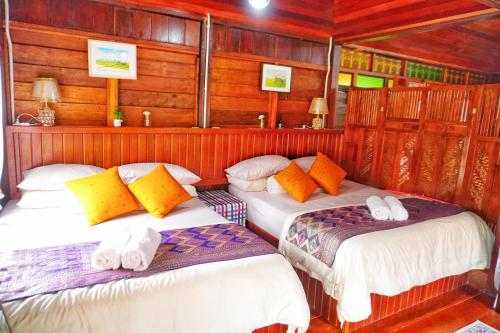 two beds in a room with wooden walls at Pondok Panglima Awang in Pantai Cenang