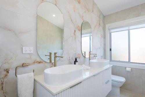 a white bathroom with two sinks and a mirror at 2 Ulmarra in Manning Point
