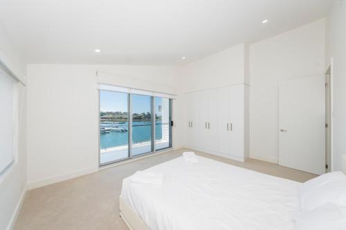 a bedroom with a large white bed and a large window at 2 Ulmarra in Manning Point