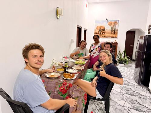 a group of people sitting around a table eating food at Midigama Lucky Villa in Midigama East