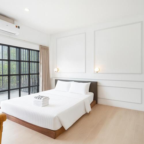 a white bedroom with a large bed and windows at Ban Rub Lom Pool Villa 3 difference villas in Rayong