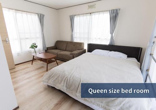 a white bedroom with a bed and a couch at The Emu Park Tomiyoshi in Kanie