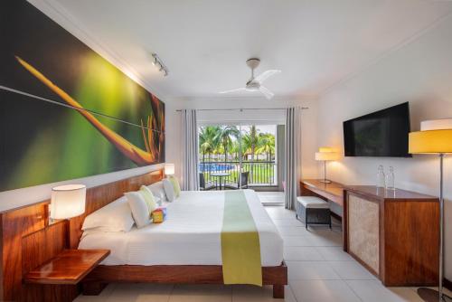 a bedroom with a large bed and a television at Tamassa Bel Ombre in Bel Ombre