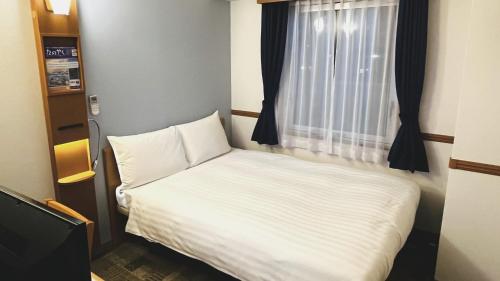 a small bed in a room with a window at Toyoko Inn Kobe Sannomiya-eki Higashi in Kobe