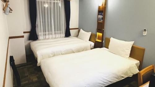 a room with two beds and a window at Toyoko Inn Kobe Sannomiya-eki Higashi in Kobe