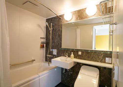 a bathroom with a sink and a toilet and a mirror at Smile Hotel Tokyo Asagaya in Tokyo