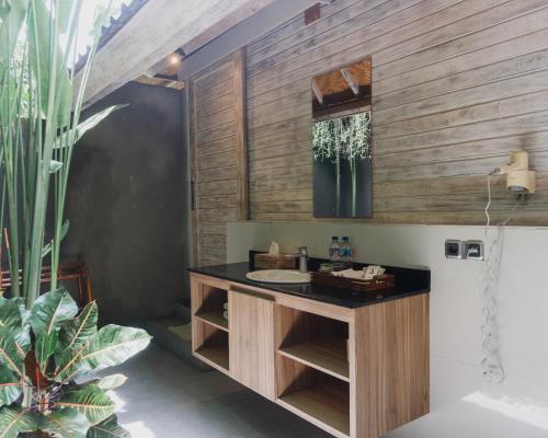 a bathroom with a sink and a wooden wall at The Angkal Resort in Nusa Penida
