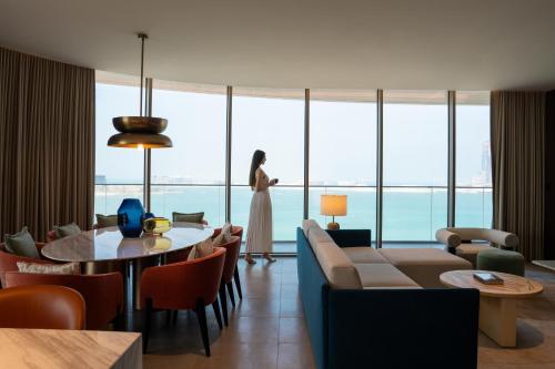 a woman standing in a room with a table and chairs at SO Ras Al Khaimah Hotel & Resort-Ultra All Inclusive in Ras al Khaimah