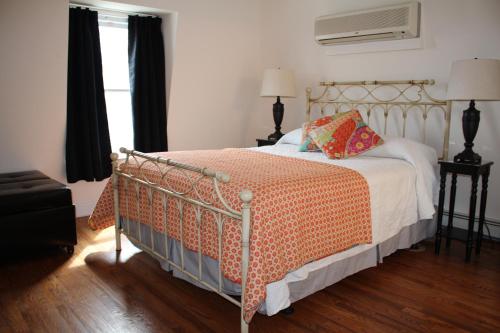 a bedroom with a bed with an orange and white comforter at Tandem Bike Inn in Belmar
