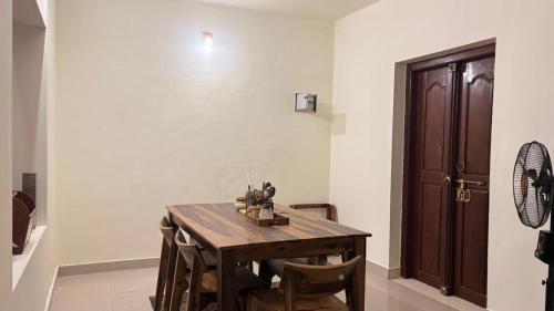 a dining room with a wooden table and chairs at Casa Areca in Cheruthuruthi