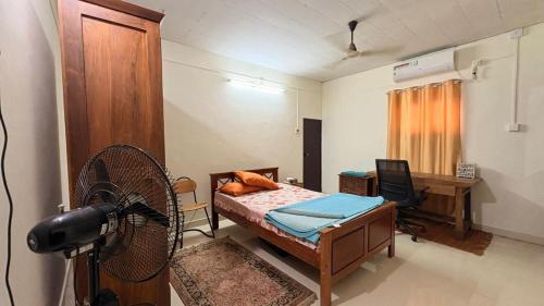 a room with a bed and a desk and a fan at Casa Areca in Cheruthuruthi