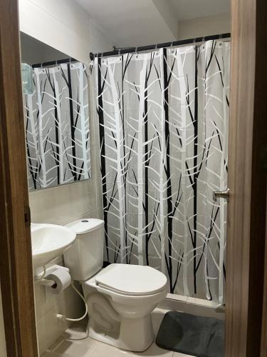 a bathroom with a toilet and a shower curtain at Alameda del rio Turpial in Barranquilla