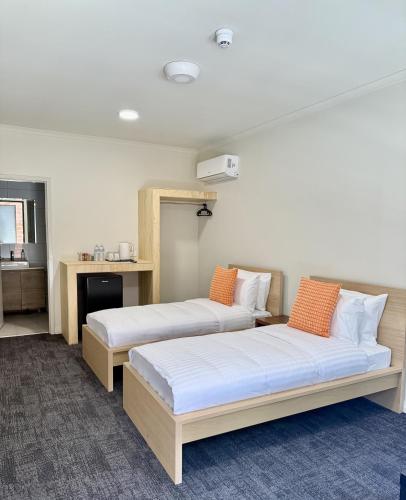 two beds with orange pillows in a room at Gallery Boutique Hotel in Fremantle