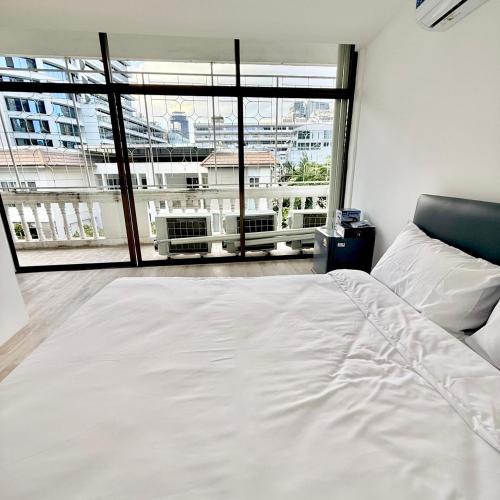 a white bed in a room with a large window at Rest Inn Silom - BTS Chong Nonsi in Bang Rak