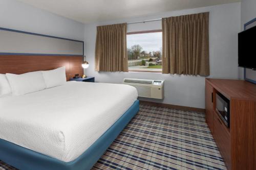 a hotel room with a bed and a flat screen tv at AmericInn by Wyndham Green Bay West in Green Bay