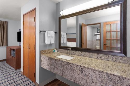 a bathroom with a sink and a large mirror at AmericInn by Wyndham Green Bay West in Green Bay