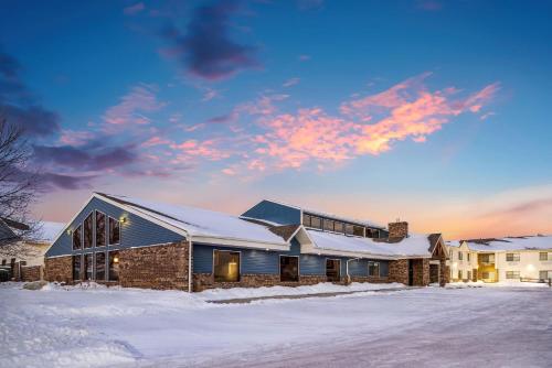a house in the snow with a sunset at AmericInn by Wyndham Aberdeen Event Center in Aberdeen