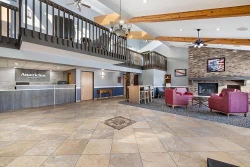 an open lobby with red chairs and a fireplace at AmericInn by Wyndham Aberdeen Event Center in Aberdeen