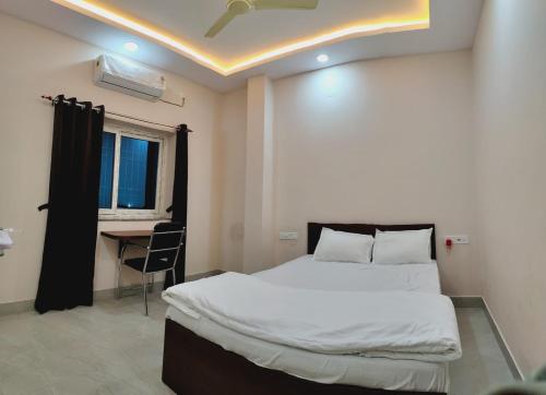 a bedroom with a bed and a table and a window at Swastiik Inn in Belpahār