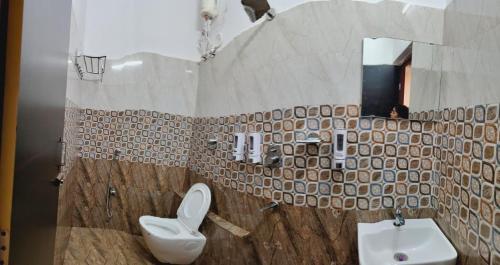 a bathroom with a sink and a toilet and a mirror at Swastiik Inn in Belpahār