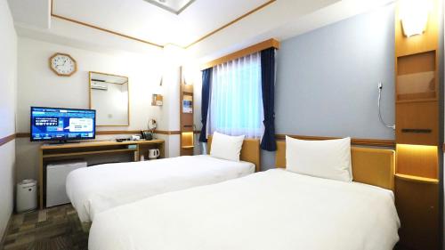 a hotel room with two beds and a television at Toyoko Inn Kumamoto-jyo Toricho Suji in Kumamoto
