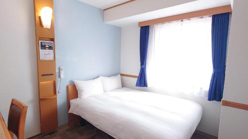 a bedroom with a white bed and a window at Toyoko Inn Kumamoto-jyo Toricho Suji in Kumamoto