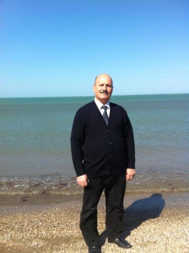 a man in a suit and tie standing on the beach at Hasanovs Villa in Baku