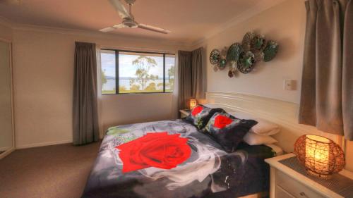 Un dormitorio con una cama con una rosa roja. en Dolphin Waters, en Tin Can Bay