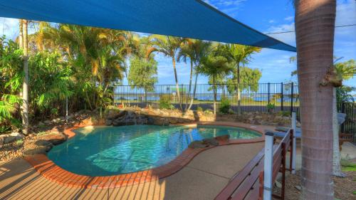 a swimming pool in a yard with a blue umbrella at Dolphin Waters in Tin Can Bay