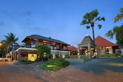 ein großes Haus mit Palmen davor in der Unterkunft Bali Niksoma Boutique Beach Resort in Legian