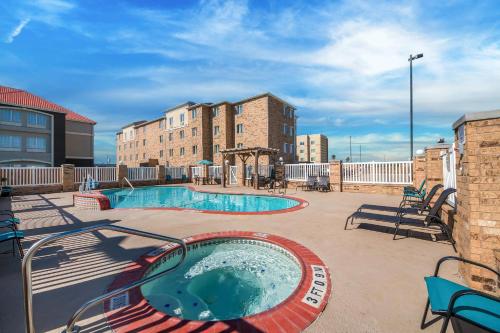 a swimming pool on a patio with chairs and a building at Comfort Suites Corpus Christi Central in Corpus Christi