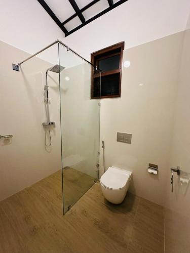 a bathroom with a toilet and a glass shower at The Leaf Cinnamon villa in Hikkaduwa