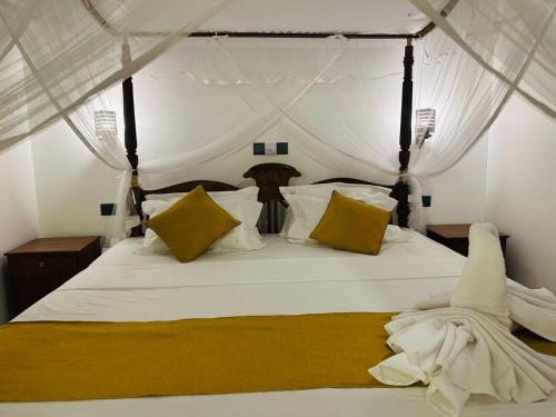a bedroom with a bed with white sheets and yellow pillows at The Leaf Cinnamon villa in Hikkaduwa