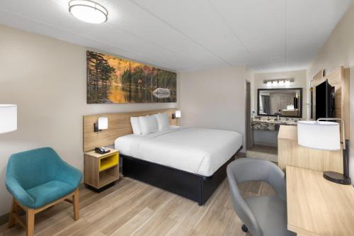 a hotel room with a bed and a blue chair at Days Inn by Wyndham Charleston WV in Charleston