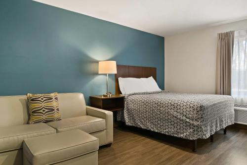 a hotel room with a bed and a couch at WoodSpring Suites East Lansing - University Area in East Lansing