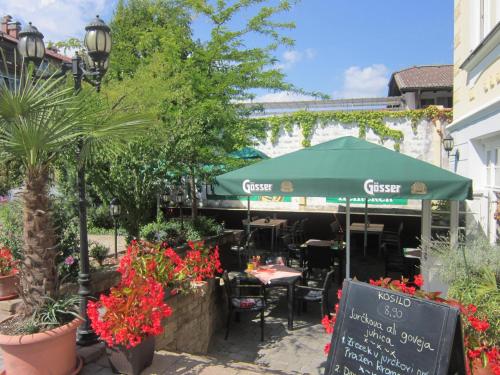 a cafe with a green umbrella and tables and plants at Guest House Veronika in Kočevje