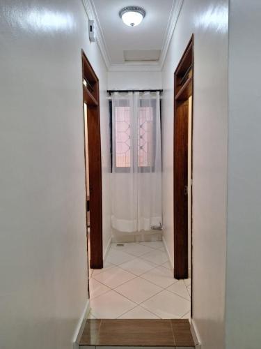 a hallway with a door to a bathroom with a window at Serena10 in Mombasa