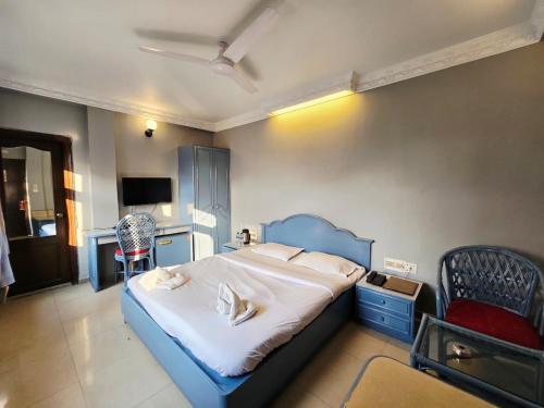 a bedroom with a blue bed and a chair at Park Palace Hotel in Kolkata