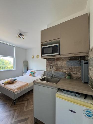 a small kitchen with a bed and a sink at Dalston Luxe Studios, 10 minutes away from Liverpool Train Station in London