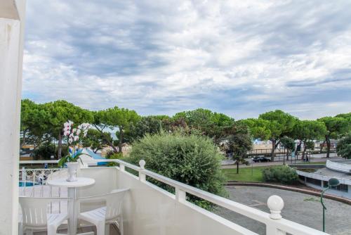a balcony with a table and chairs and trees at Hotel Miramare in Lignano Sabbiadoro