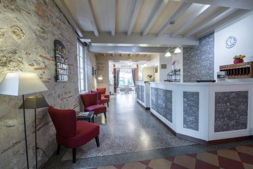 a lobby with red chairs and a chalkboard on the wall at Logis Hotels - Au Colombier du Touron in Brax