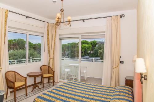 a bedroom with a bed and a balcony with a table at Hotel Miramare in Lignano Sabbiadoro